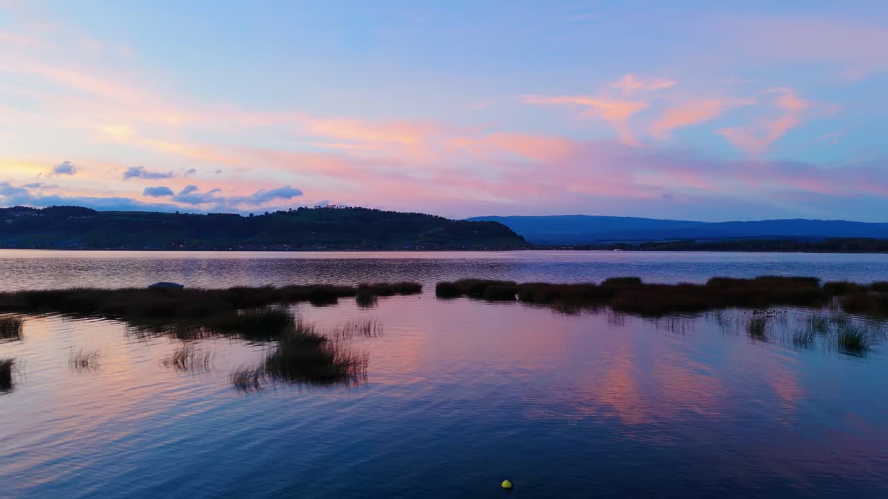 Dronefligth over boats and Landscape in at the lake in Murten Switzerland during bluehour.