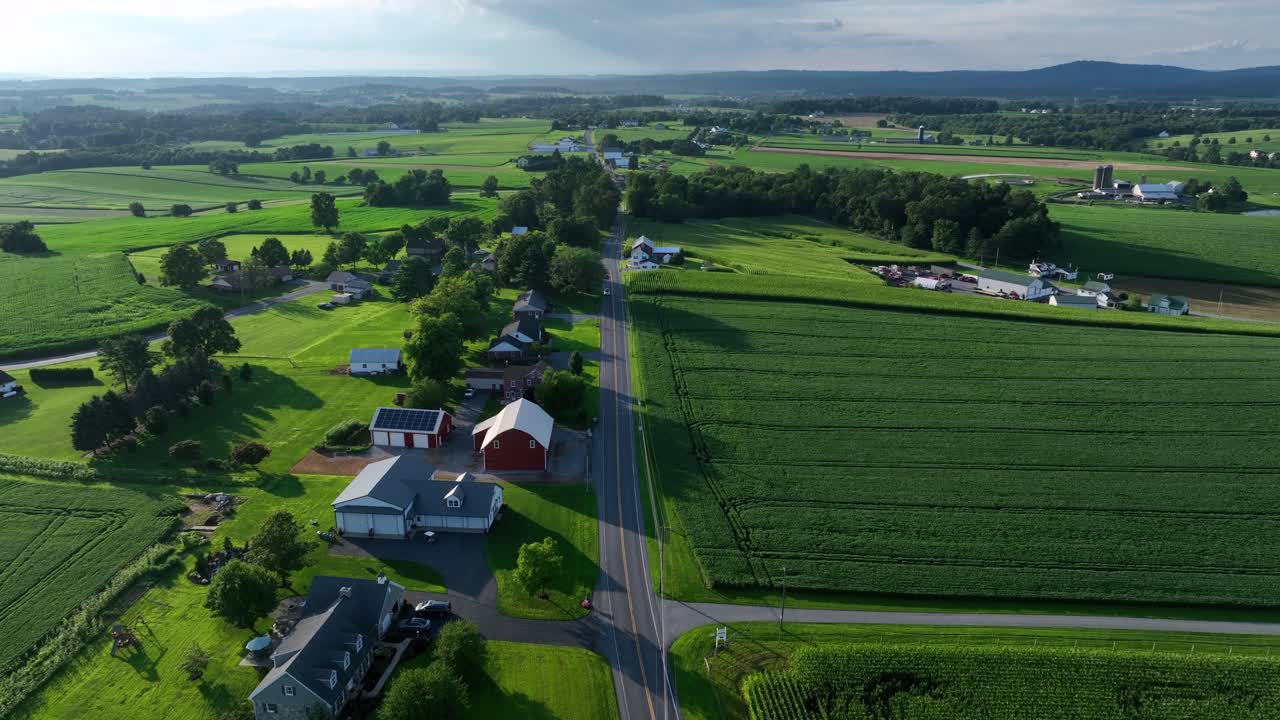 Idyllic and quiet rural landscape with Main Street in suburb town of America. Farmsteads and homes in quaint neighborhood of USA. Sunset time. Aerial Birds Eye forward