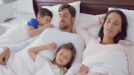 Family-sleeping-together-on-bed-in-bedroom-at-home-4k