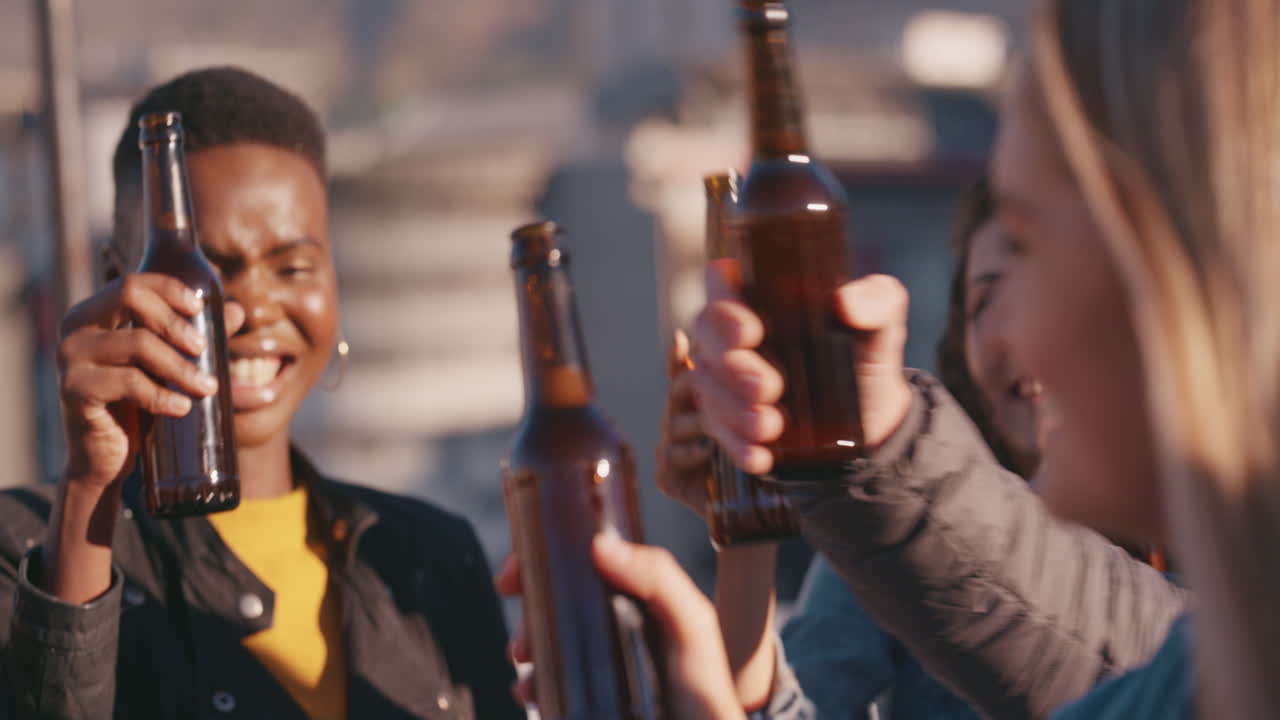 un gruppo di amici felici che festeggiano su un tetto fanno un brindisi bevono birra si godono la celebrazione della riunione nel fine settimana si riuniscono al tramonto