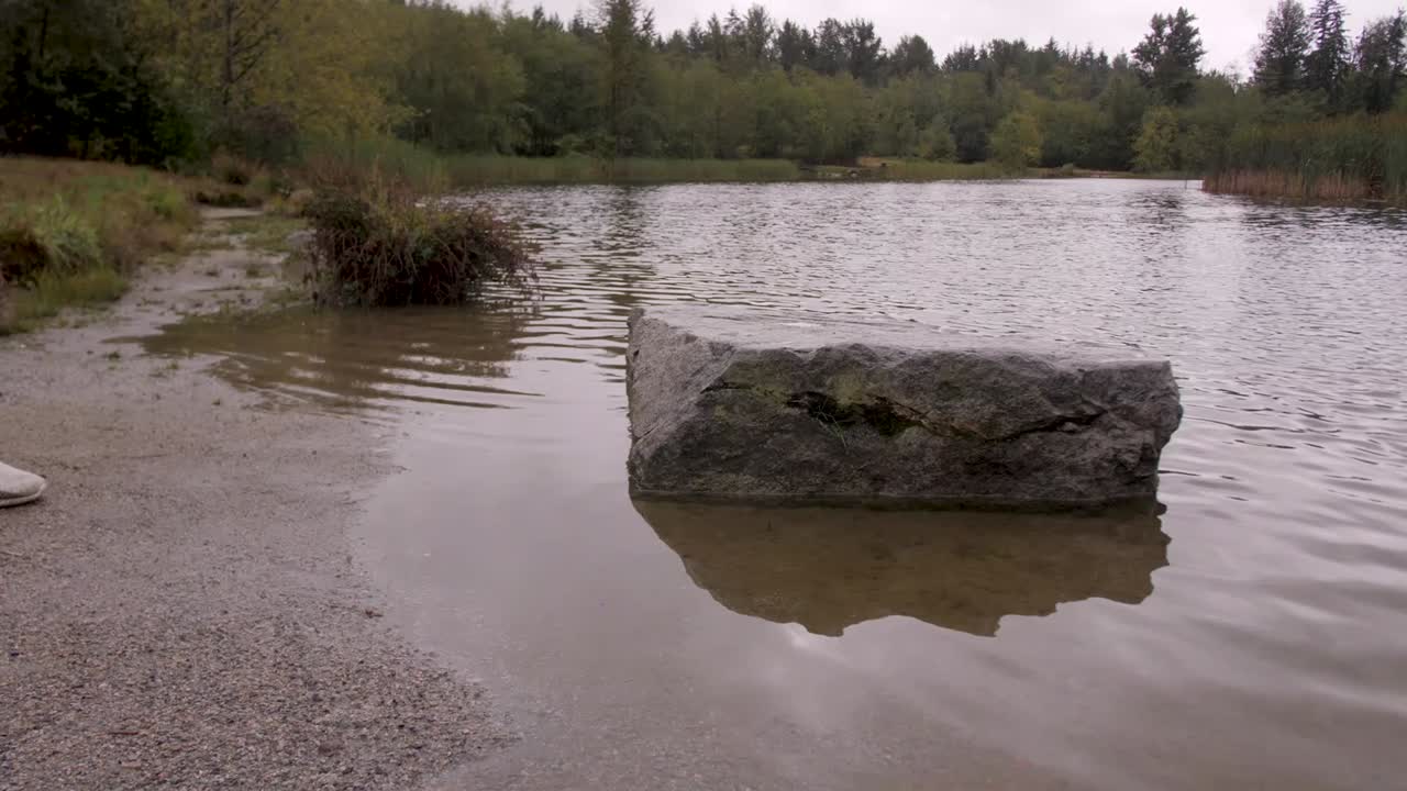 En mand træder op på en stor sten i en flod