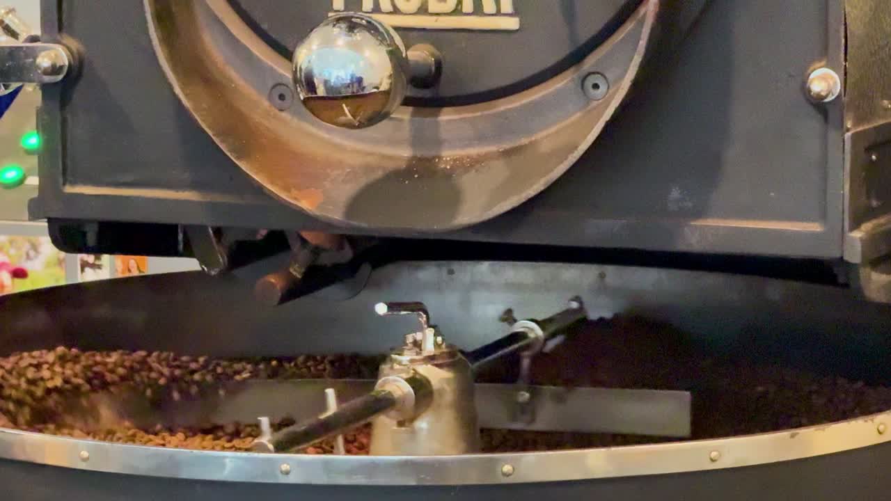 Coffee beans rotating in a roasting machine at a New Zealand cafe. Warm lighting enhances the industrial setting