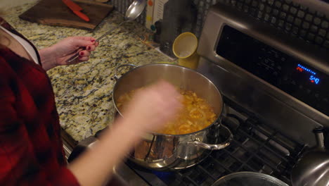 attractive woman lifts lid off of pot of ciopini and stirs closeup