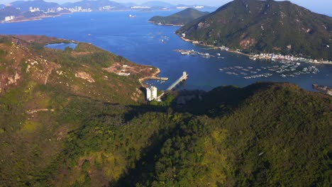 Drone-shot,-traveling-to-the-left,-of-a-industrial-building-front-of-a-fisher-village-during-the-day-on-a-tropical-island