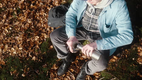 joven sirviendo café en su taza en un soleado día de otoño