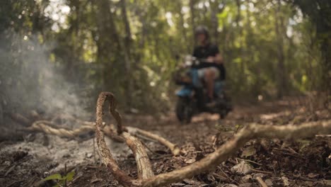 dos jinetes masculinos conduciendo a lo largo del camino en el bosque con ramitas secas humeantes quemadas dejadas por los campistas