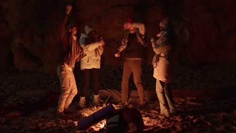 friends dancing around a campfire at night