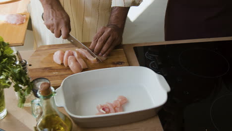 man chopping chicken breast for cooking