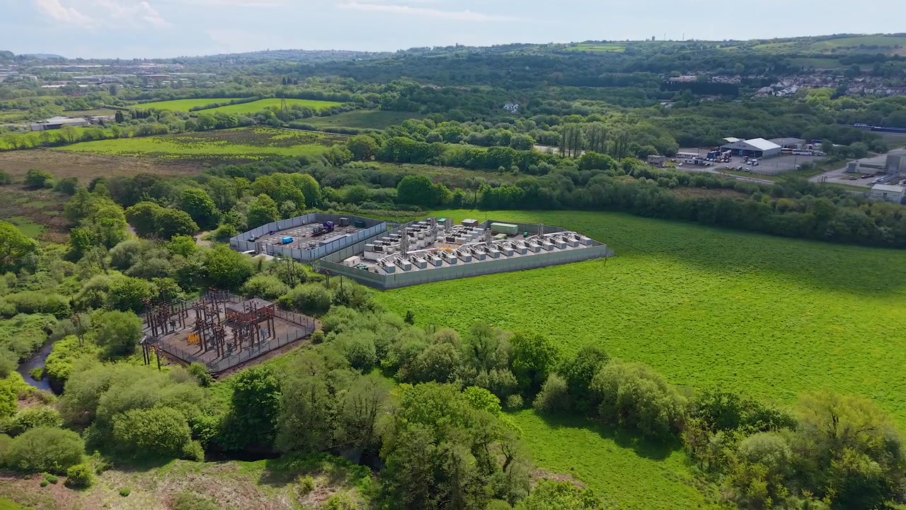 Retreating Drone View of Modern Gas Peaking Plant with exhaust stacks, generators, cooling systems. Facility provides rapid-response electricity to the grid during peak demand. Energy infrastructure.