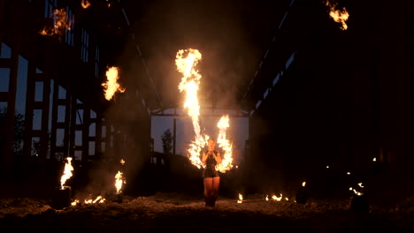 Professionelle-Feuershow-Im-Alten-Hangar-Der-Flugzeugshow-Professionelle-Zirkusartisten,-Drei-Frauen-In-Lederkombis-Und-Ein-Mann-Mit-Zwei-Flammenwerfern.