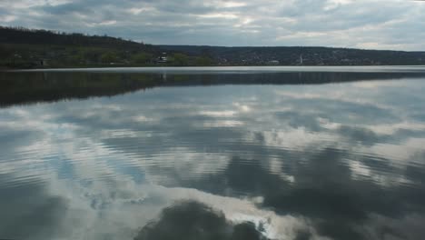 river or lake landscape with reflections of cloudy sky in water. ripple surface of calm water at evening or morning time