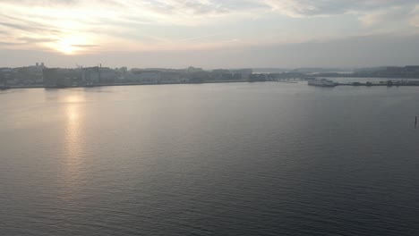 Una-Hermosa-Toma-De-Imágenes-Aéreas-Sobre-El-Agua-Acercándose-A-La-Ciudad-Naval-De-Karlskrona,-Suecia-En-Un-Día-Nublado-Cuando-El-Sol-Está-A-Punto-De-Ponerse