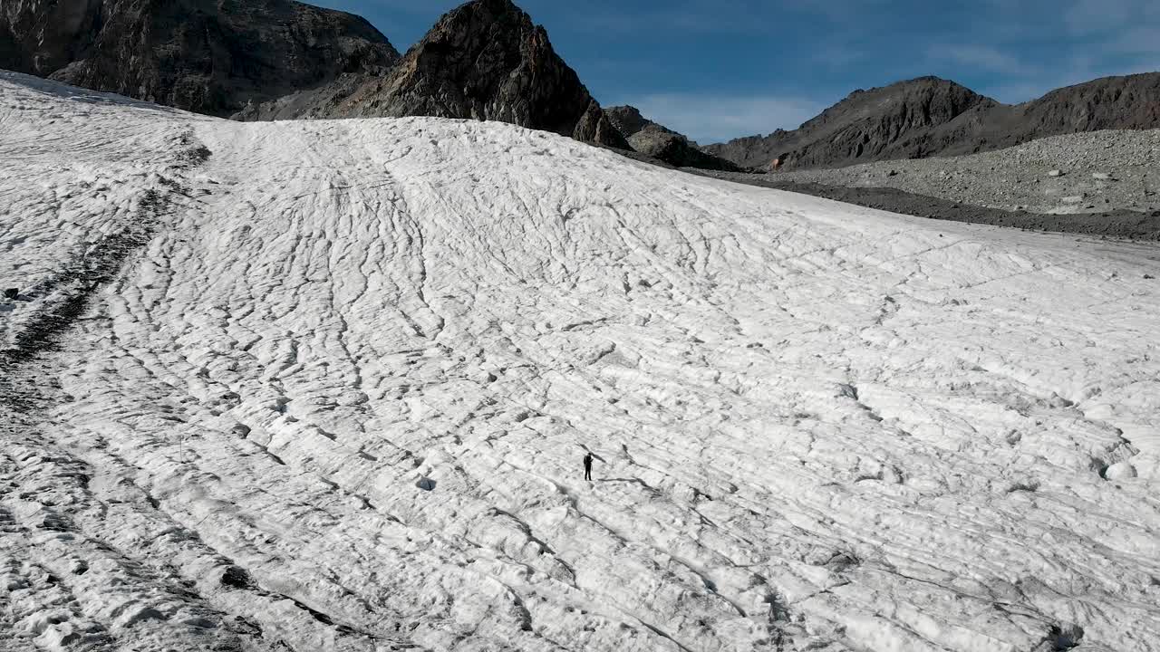 воздушный перелет над туристом, проходящим по льду ледника алалин недалеко от саас-фе в вале, швейцария в солнечный день в швейцарских альпах