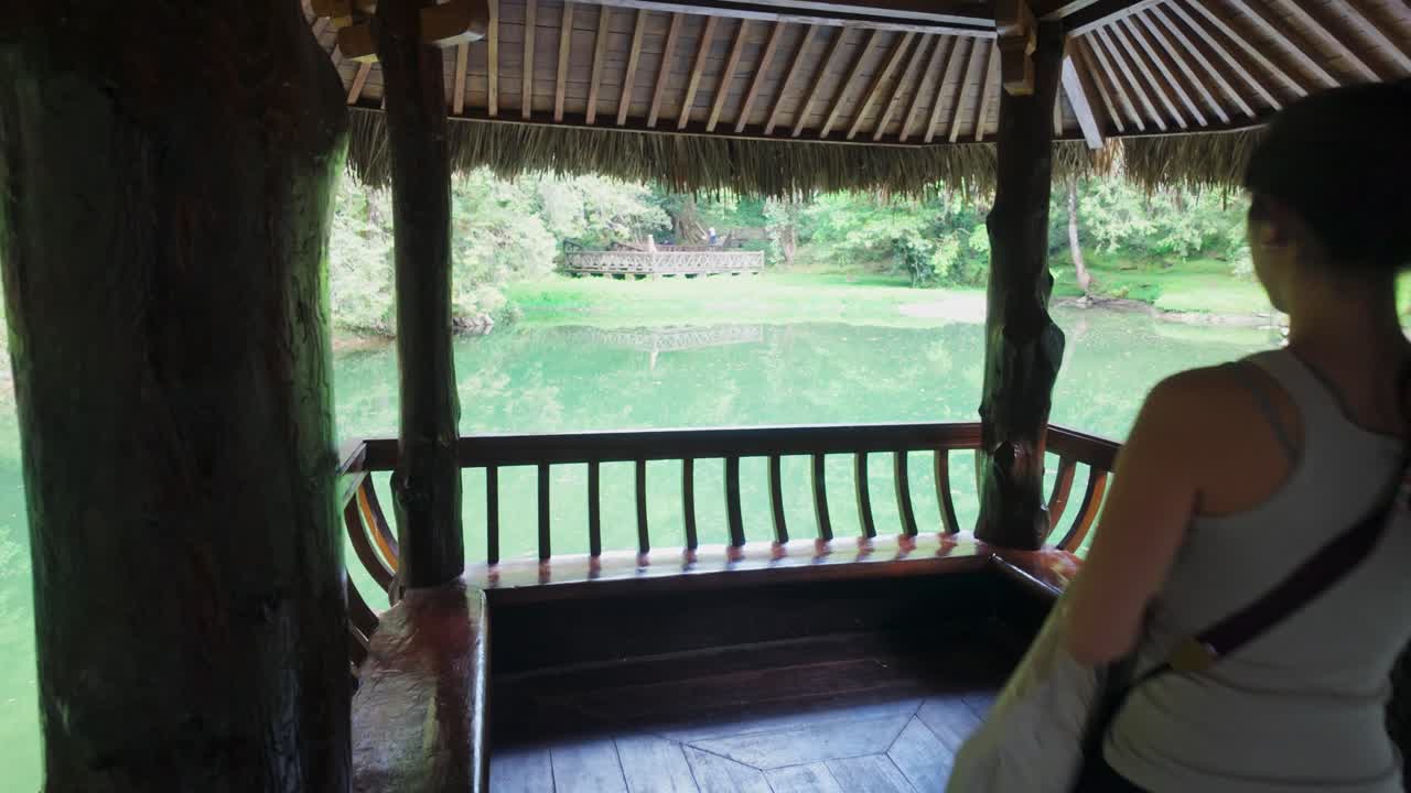Woman sits down in serene gazebo view over peaceful pond in Alishan Township, Taiwan