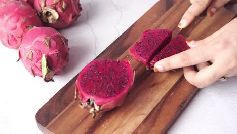 slicing dragon fruit on a wooden cutting board