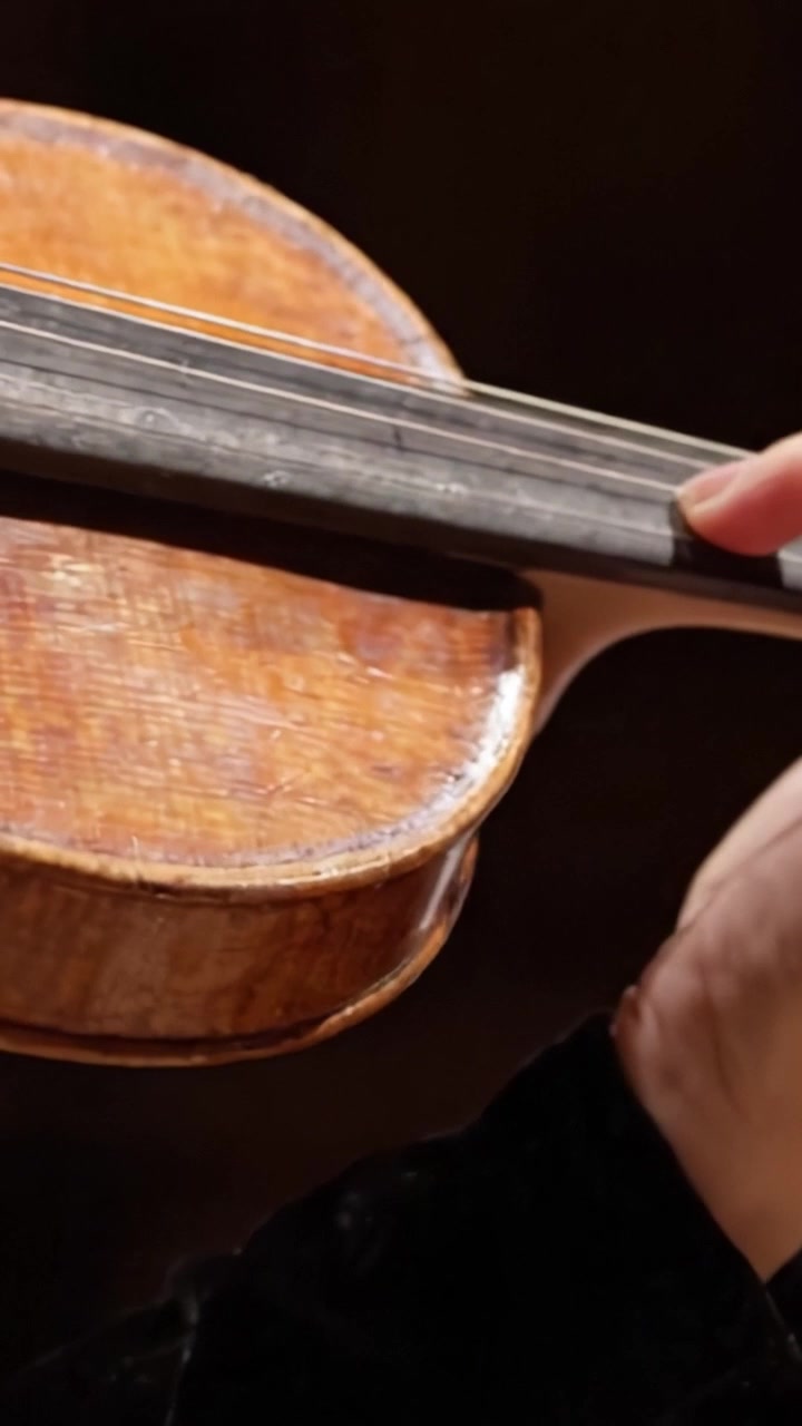 A Close-Up Shot of a Hand Gripping a Beautifully Crafted Violin, Capturing the Intricacies of the Instrument's Design and Technique in Impressive Detail