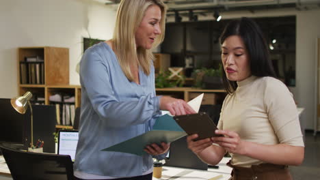 mujeres de negocios caucásicas y asiáticas revisan documentos en una oficina