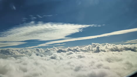 vista por la ventana de un avión volando sobre nubes blancas bajo un cielo azul