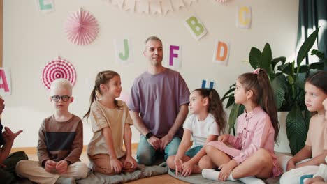 lección entre los niños de la escuela primaria con el maestro. los niños en edad escolar se sientan alrededor de su maestro masculino adulto y lo escuchan en el fondo de decoraciones dedicadas al primer día de escuela