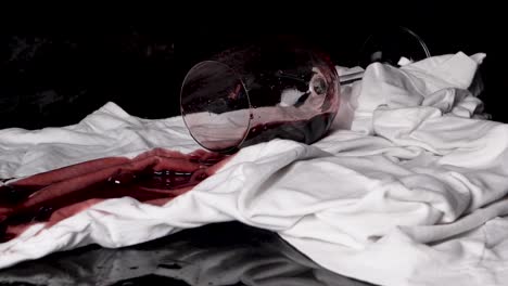 a full glass of wine falls over a tablecloth and the liquid sucks into the material