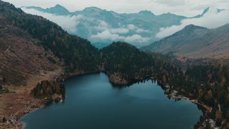 Flying-over-autumn-moody-mountain-lake-Cavloc-in-Switzerland,-Maloja