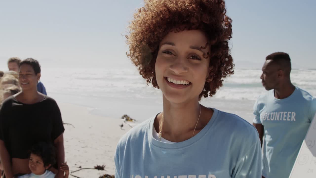 Front view of African american female volunteer looking at camera on the beach 4k