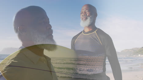 composite of african american senior man stretching arms, and carrying surfboard on sunny beach