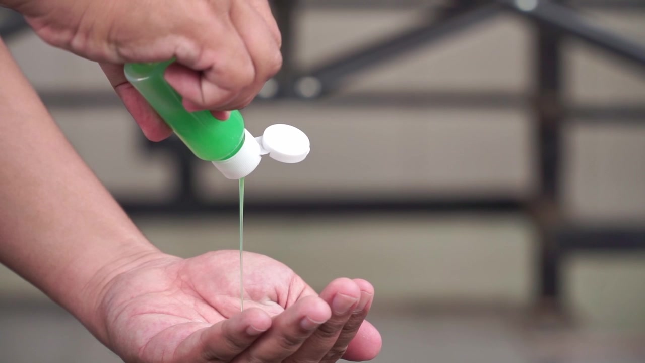 Persona che versa sapone liquido nel palmo, igiene delle mani, routine di igienizzazione, focus su sanità e pulizia.