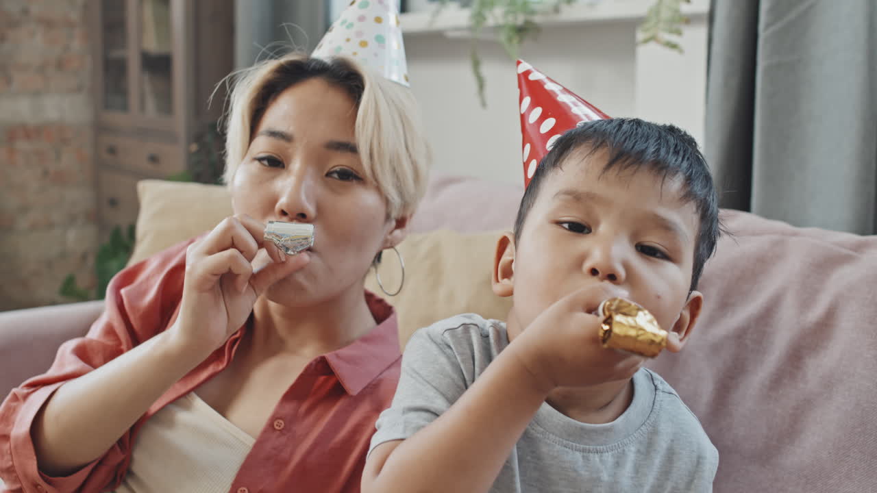 Asian Mother and Son Blowing Party Horns at Camera