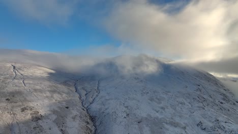 clouds moving on mountain summit covered in light snow with altitude rise towards cloud cover