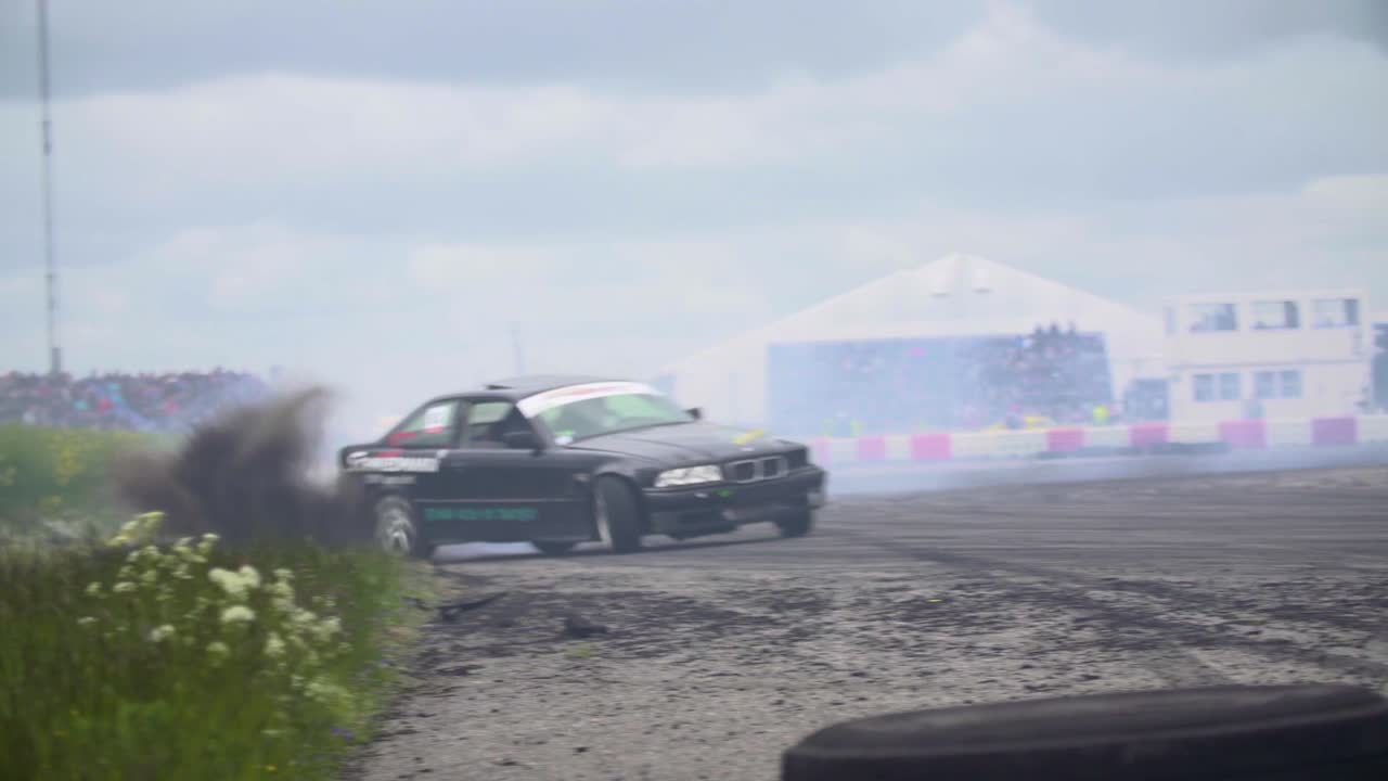 BMW E36 drifting fast and hitting the dirt off the track in a fast corner with lots of dirt flying into the air.