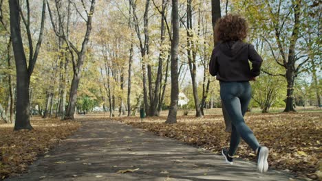 rear view of ginger woman running at the park in autumn