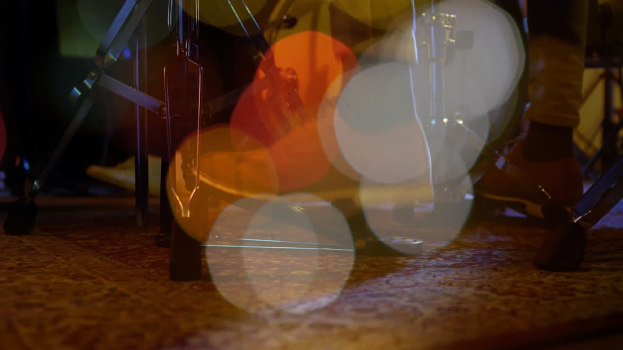 Drum hardware being animated, showing hi-hat stand and pedal pressing on patterned rug with bokeh