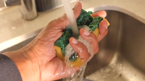 washing a cleaning sponge under running water