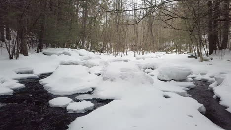 Low-flying-drone-above-a-snowy-river-in-winter