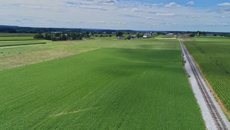 Ein-180-Grad-Blick-Auf-Reiches-Ackerland-Und-Maisfelder-Entlang-Einer-Einzigen-Eisenbahnstrecke-An-Einem-Sonnigen-Sommertag