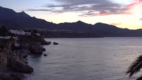 Langsamer-Schwenk-über-Meer-Und-Häuser-Bei-Sonnenuntergang-Mit-Bergen-Im-Hintergrund