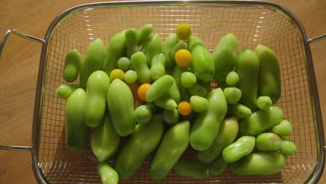 Green-organic-tomatoes-ripening-inside-in-a-metal-basket-in-sunlight