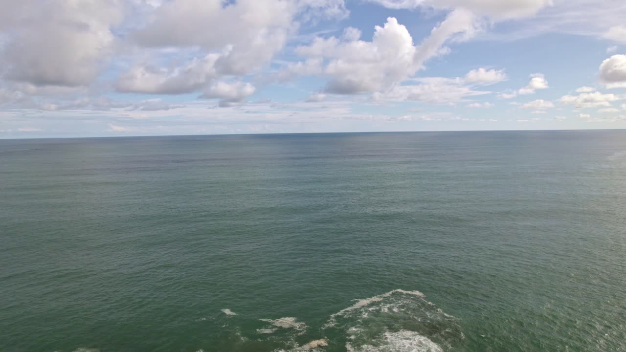 Aerial dolly in rising over rocky shore and turquoise sea on a cloudy day in in Dominicalito Beach, Costa Rica