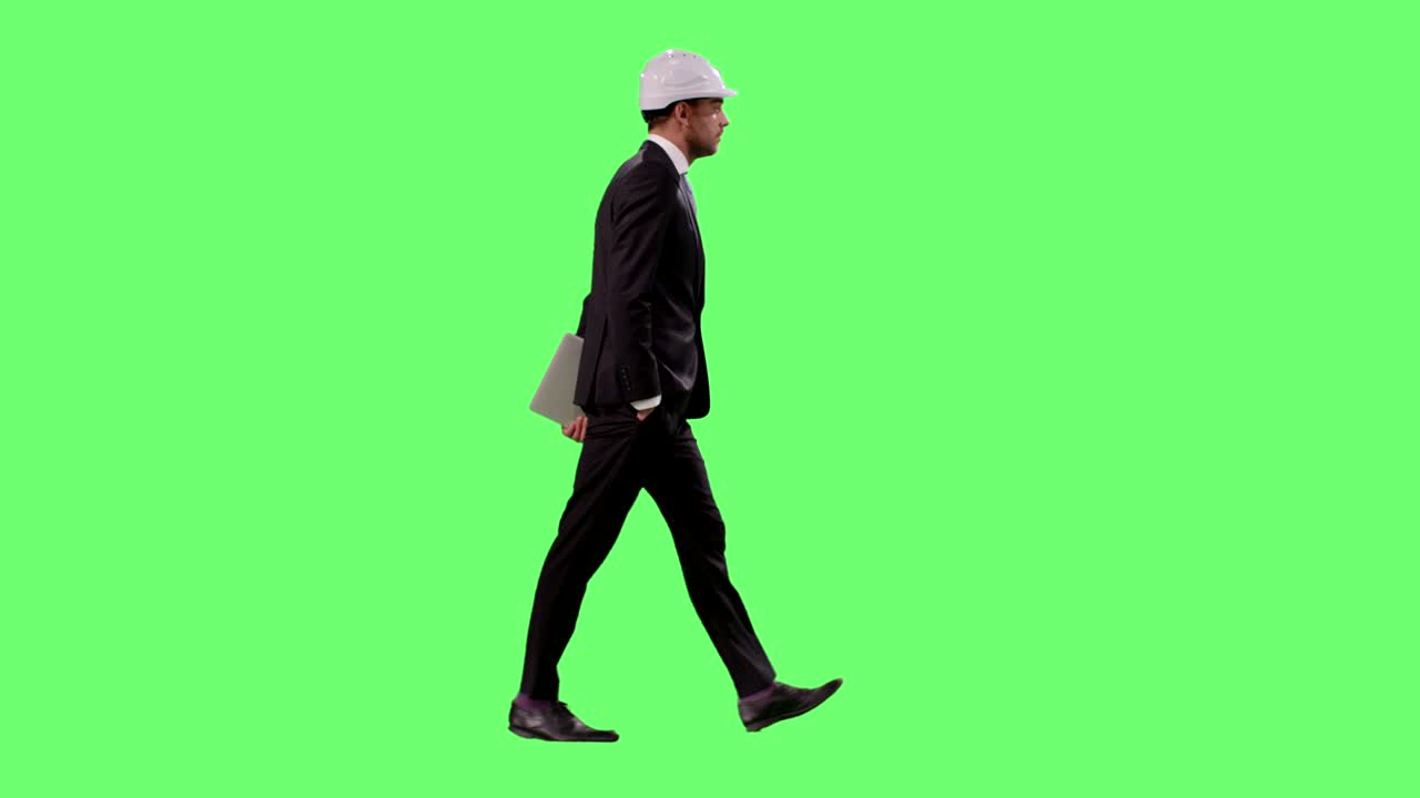 하드 과 슈트를 입은 사업가가 배경에 있는 모의 녹색 스크린에서 고 있습니다.