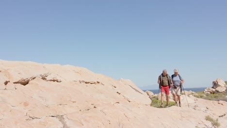 Happy-senior-biracial-couple-in-mountains-hiking,-in-slow-motion