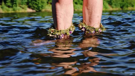 woman's feet with floral wreaths in a river