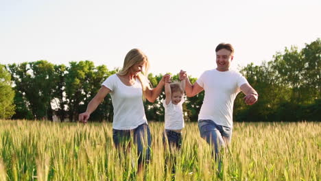 familia feliz: padre, madre e hijo, corriendo en el campo vestidos con camisetas blancas