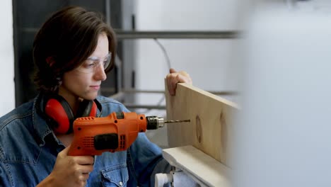 female welder using drill machine on wooden plank 4k