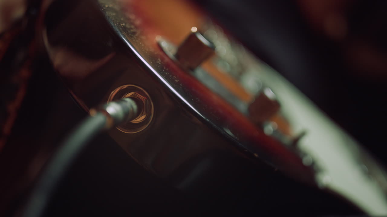 Man hand connecting guitar in concert hall. Sound engineer preparing instrument.
