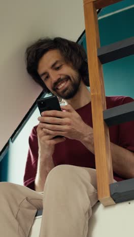man sitting on stairs using smartphone