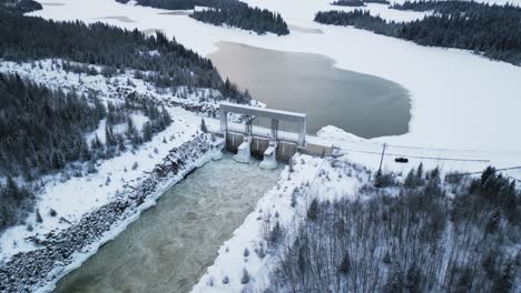 aerial drone shot rushing water notigi hydro electric power lake dam in snowy northern winter manitoba canada