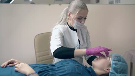 el cosmetólogo pone papel de aluminio en el tatuaje de la ceja del cliente en el salón