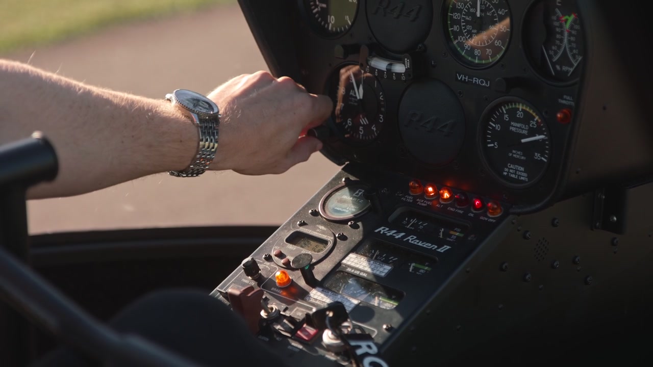 A helicopter pilot using his gauges while pressing and turning knobs and dials.