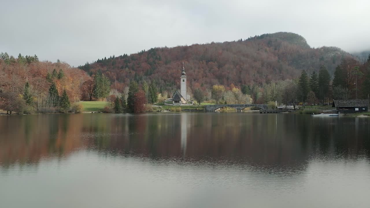 La chiesa del Lago di Bohinj in autunno con colori mozzafiato e un riflesso perfetto sul lago